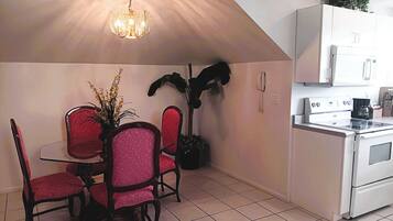 A kitchen with a dining area, white cabinets, a stove, and a chandelier.