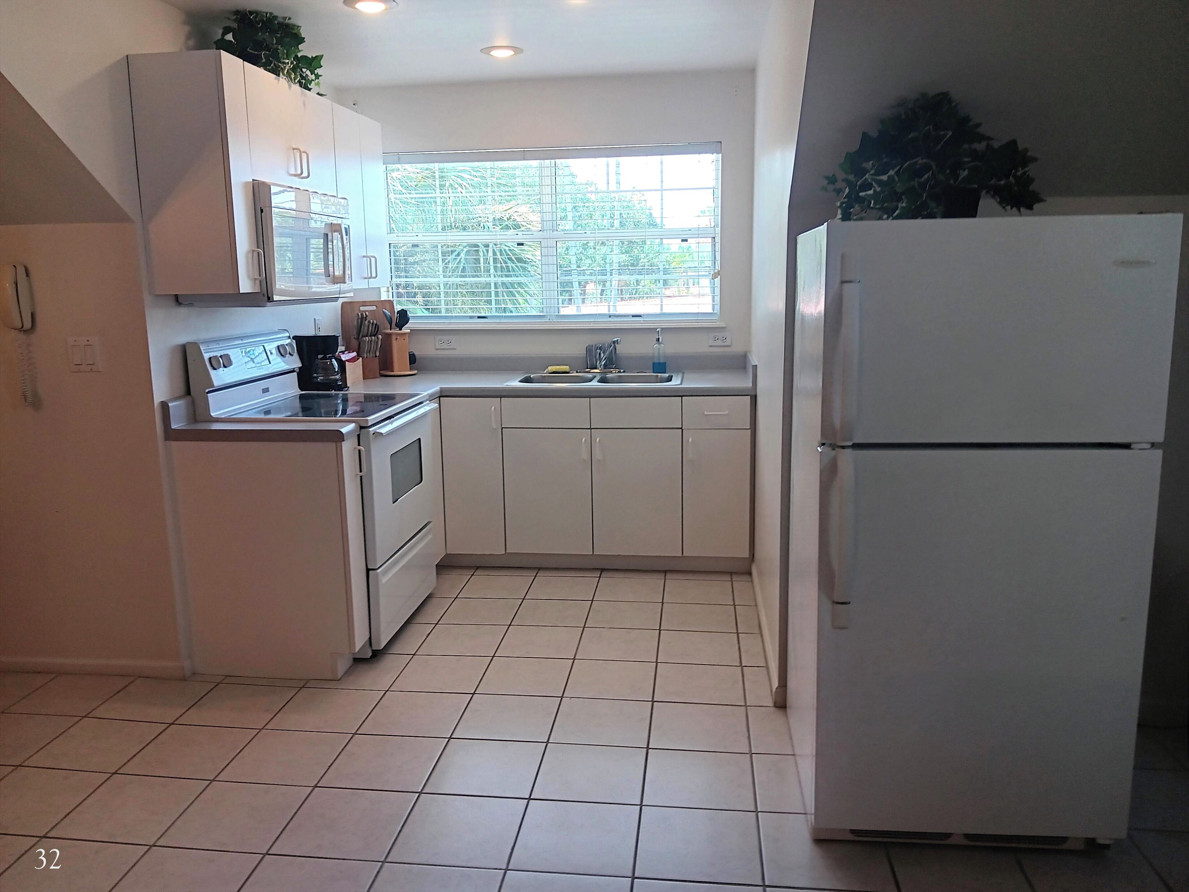 A kitchen with white cabinets, a stove, a sink, and a refrigerator.