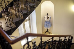A staircase with ornate metal railings and a mannequin dressed in a blue skirt and white blouse. - EA Hotel Victoria (Prague)