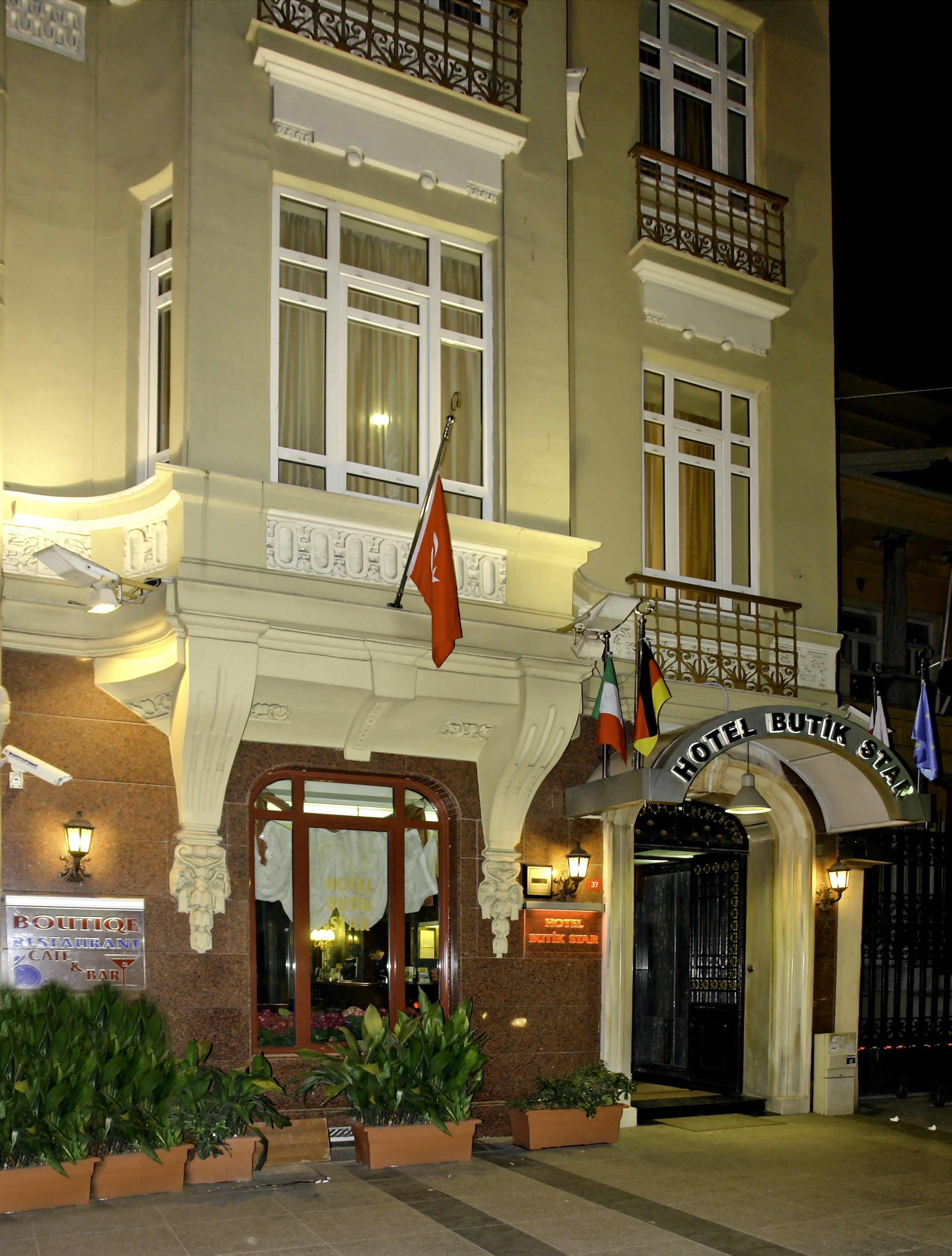 A hotel entrance with a sign reading "HOTEL BUTIK STAR," a flag, and a sign for a boutique restaurant.