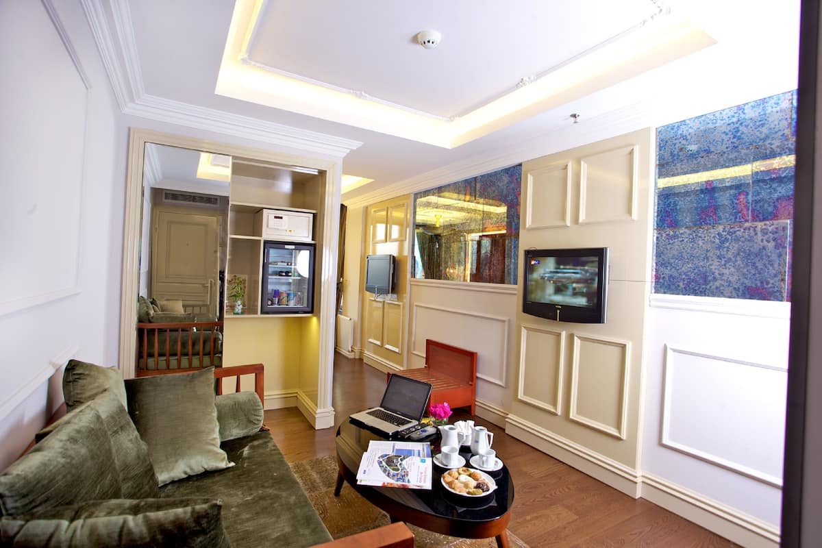 A modern living room with a sofa, a coffee table with a laptop, and a television.