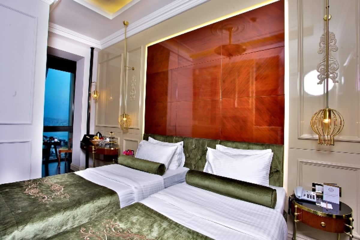 A hotel room with a large bed, a wooden headboard, and a view of the sea.