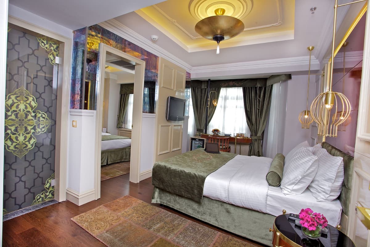 A hotel room with a bed, a desk, a television, and a decorative mirror.