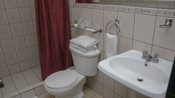 Un baño con inodoro, lavabo y cortina de ducha.