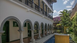 Um pátio com piscina, colunas e um edifício com varandas.