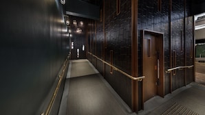 A modern hallway with a metal railing, wooden doors, and a textured wall.