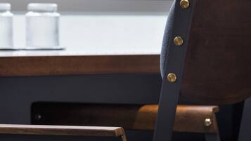 A chair with a dark seat and backrest, metal frame, and brass rivets.