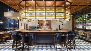 A bar area with a checkered floor, bar stools, and a central bar counter with a wine rack.