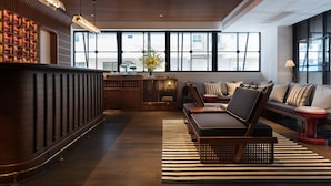 A modern hotel lobby with a reception desk, seating area, and large windows providing views of the city.
