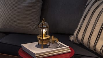A modern room with a sofa, a small red table with a lamp, and a hanging light fixture.