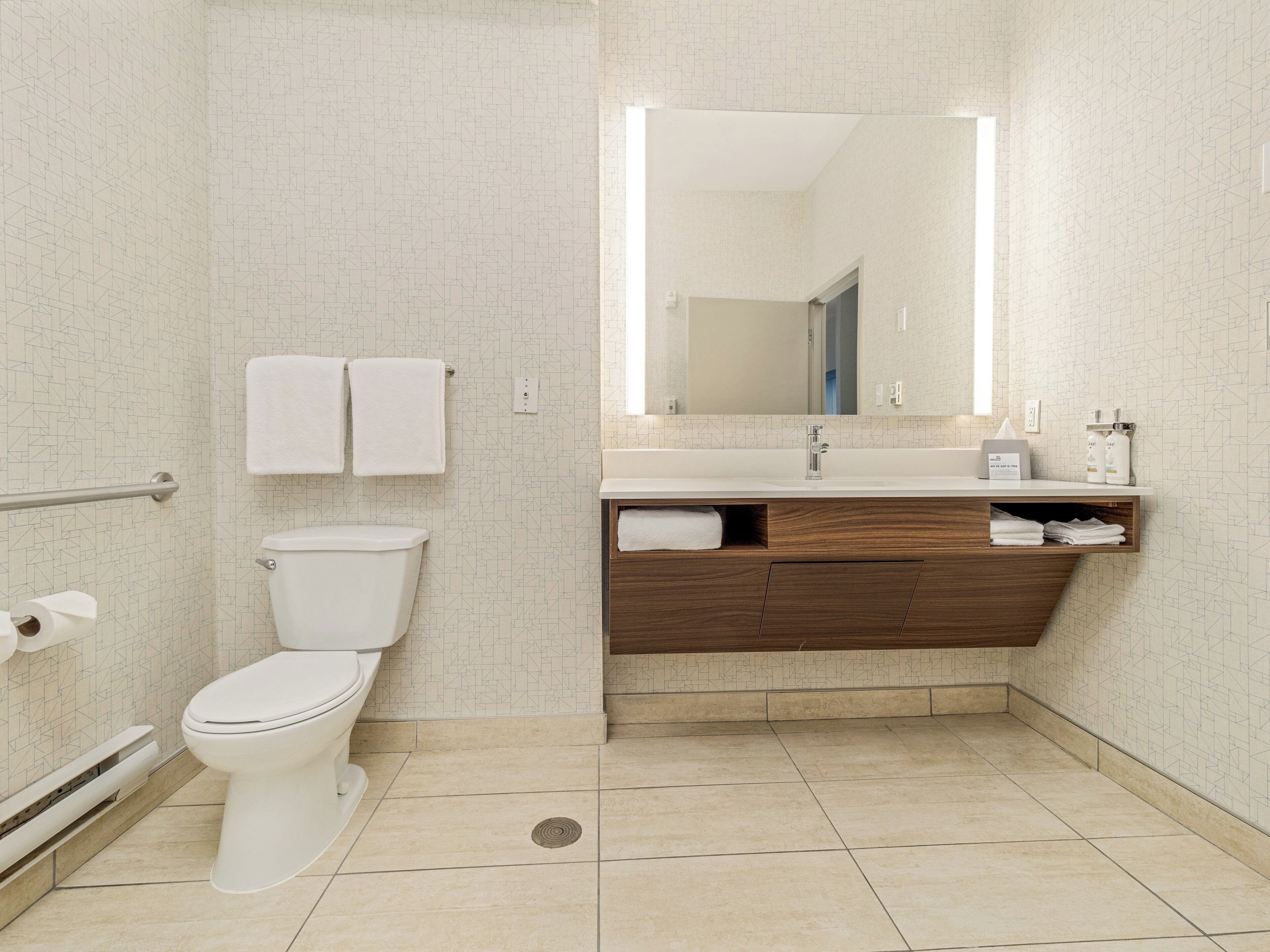 Une salle de bain moderne équipée de toilettes, d’une douche, d’un lavabo avec un miroir et d’un porte-serviettes.