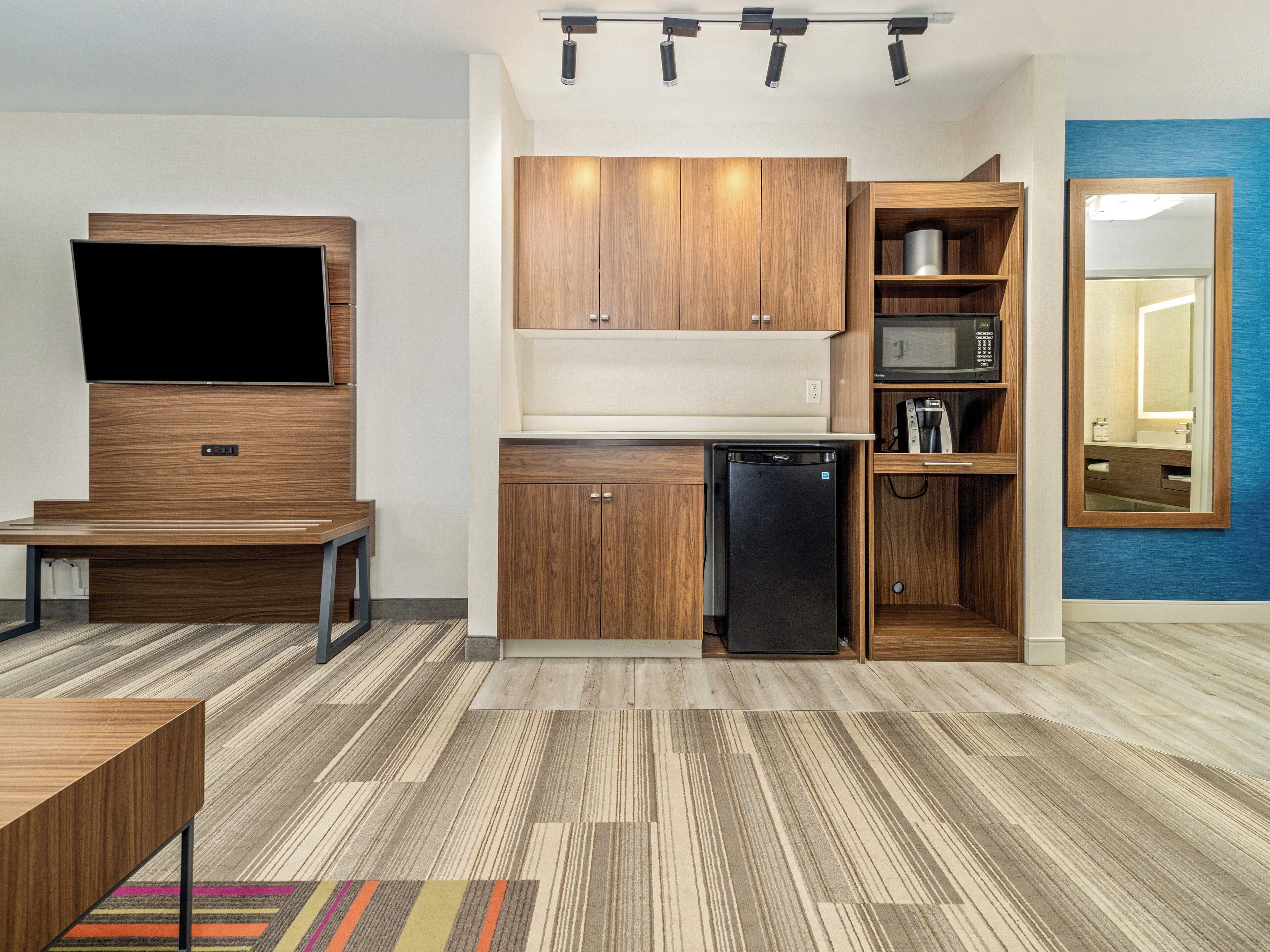 A compact kitchen with wooden cabinets, a built-in microwave, and a black refrigerator.