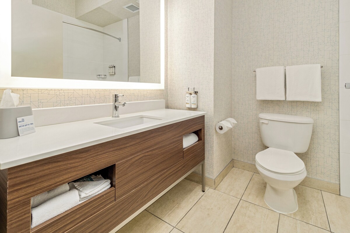 Een moderne badkamer met een grote spiegel, een wastafel, toilet en een douche.