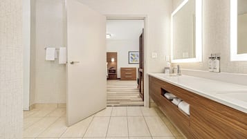 A modern bathroom with a large mirror, wooden vanity, and a shower area.