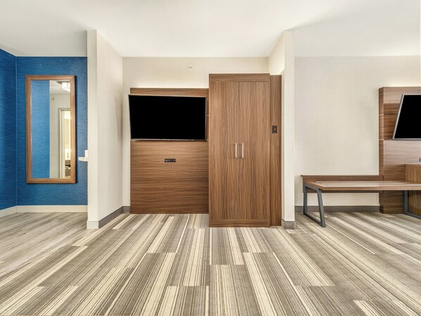 A room with a large wardrobe, a mirror, and a television.