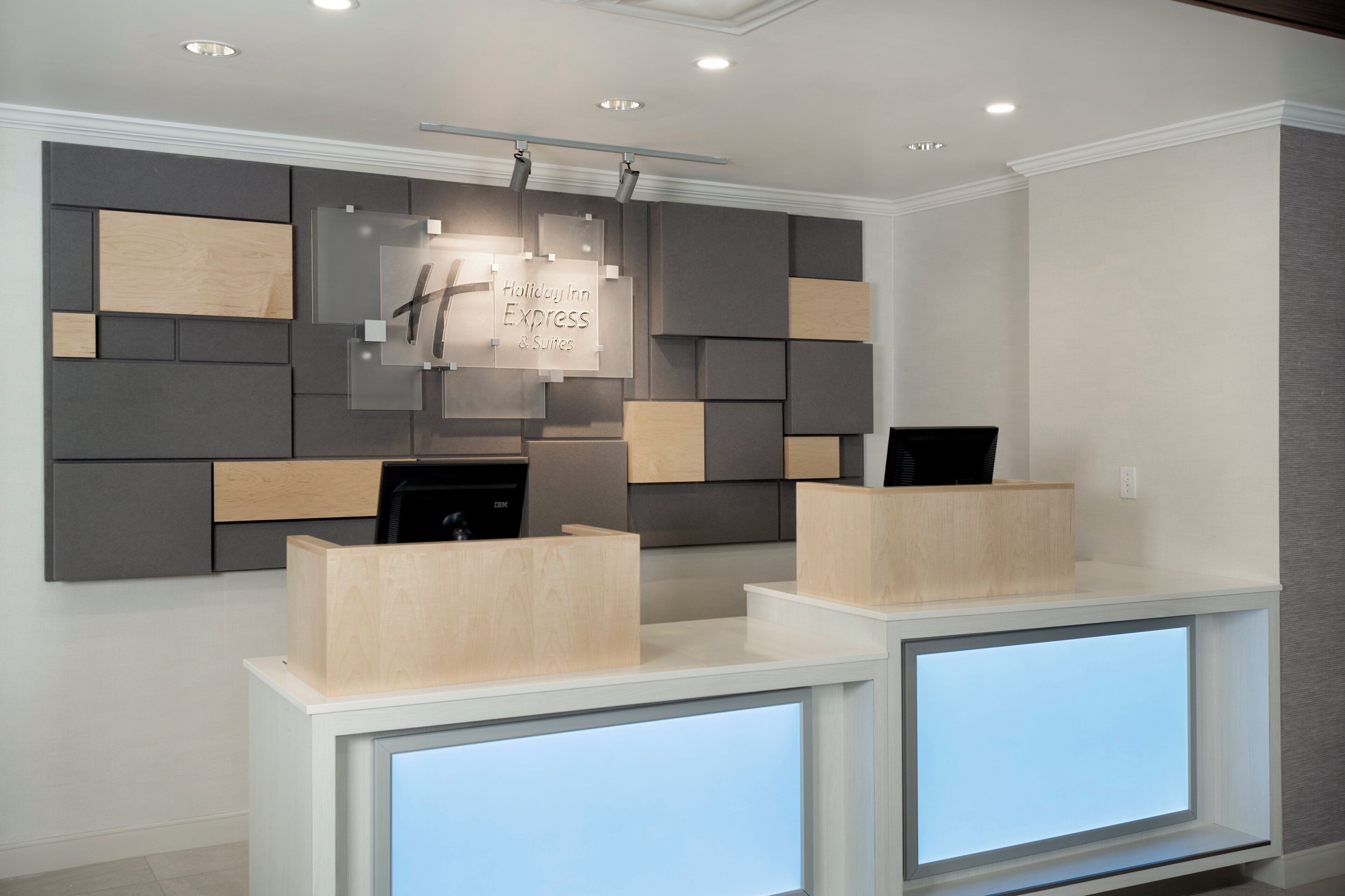 Un mostrador de recepción de diseño moderno, con un panel de vidrio que muestra el nombre y los servicios del hotel.