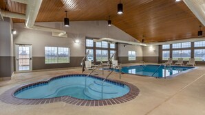 Una piscina interior con dos áreas separadas, techo de madera y ventanas amplias.