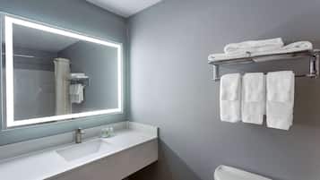 Un baño moderno con un espejo grande, lavamanos blanco y un perchero para toallas.