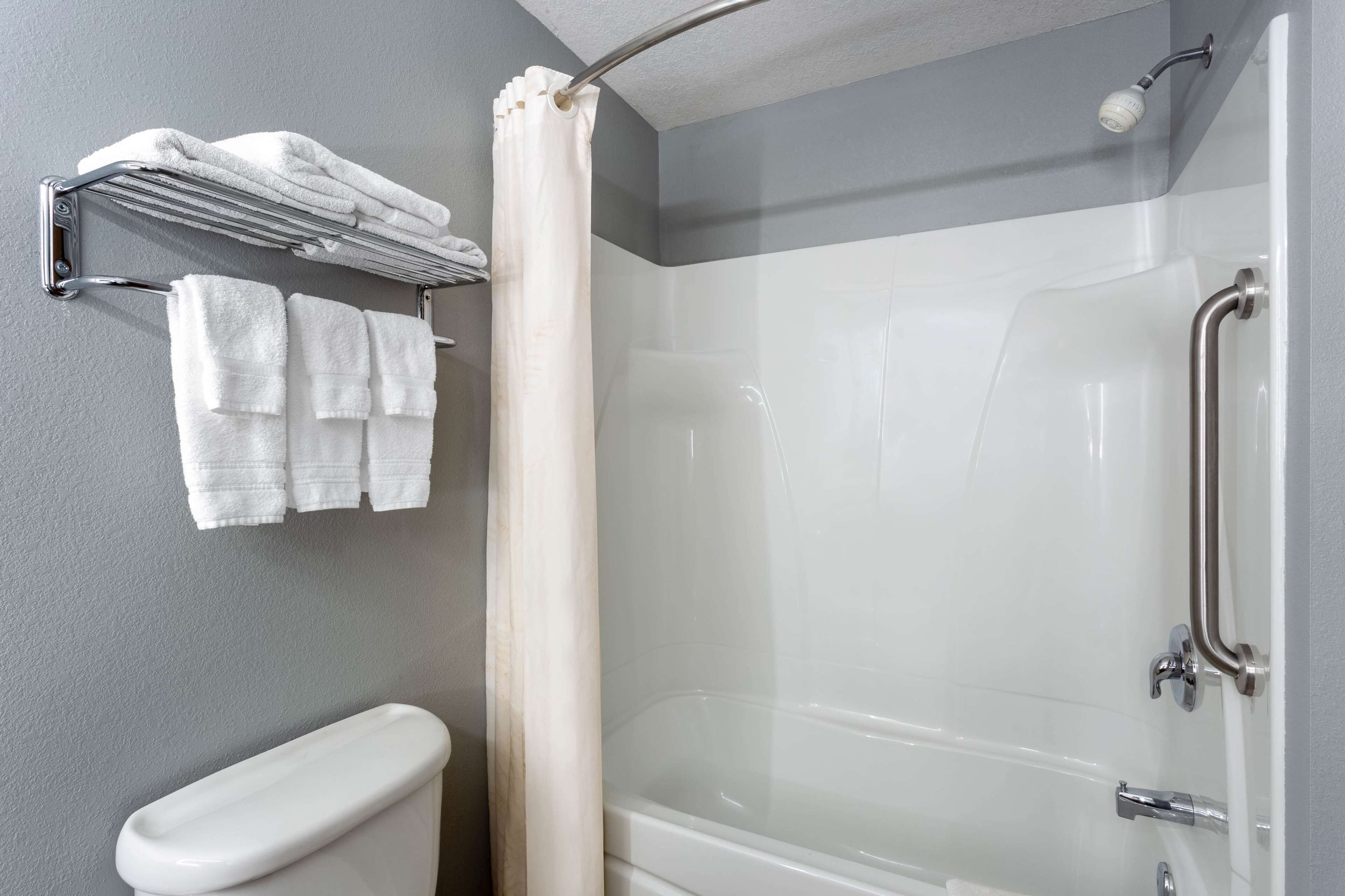 A modern bathroom with a glass-enclosed shower, a white toilet, and a towel rack with folded towels.