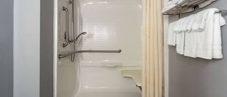 A bathroom with a bathtub, grab bars, a towel rack, and a shower curtain.