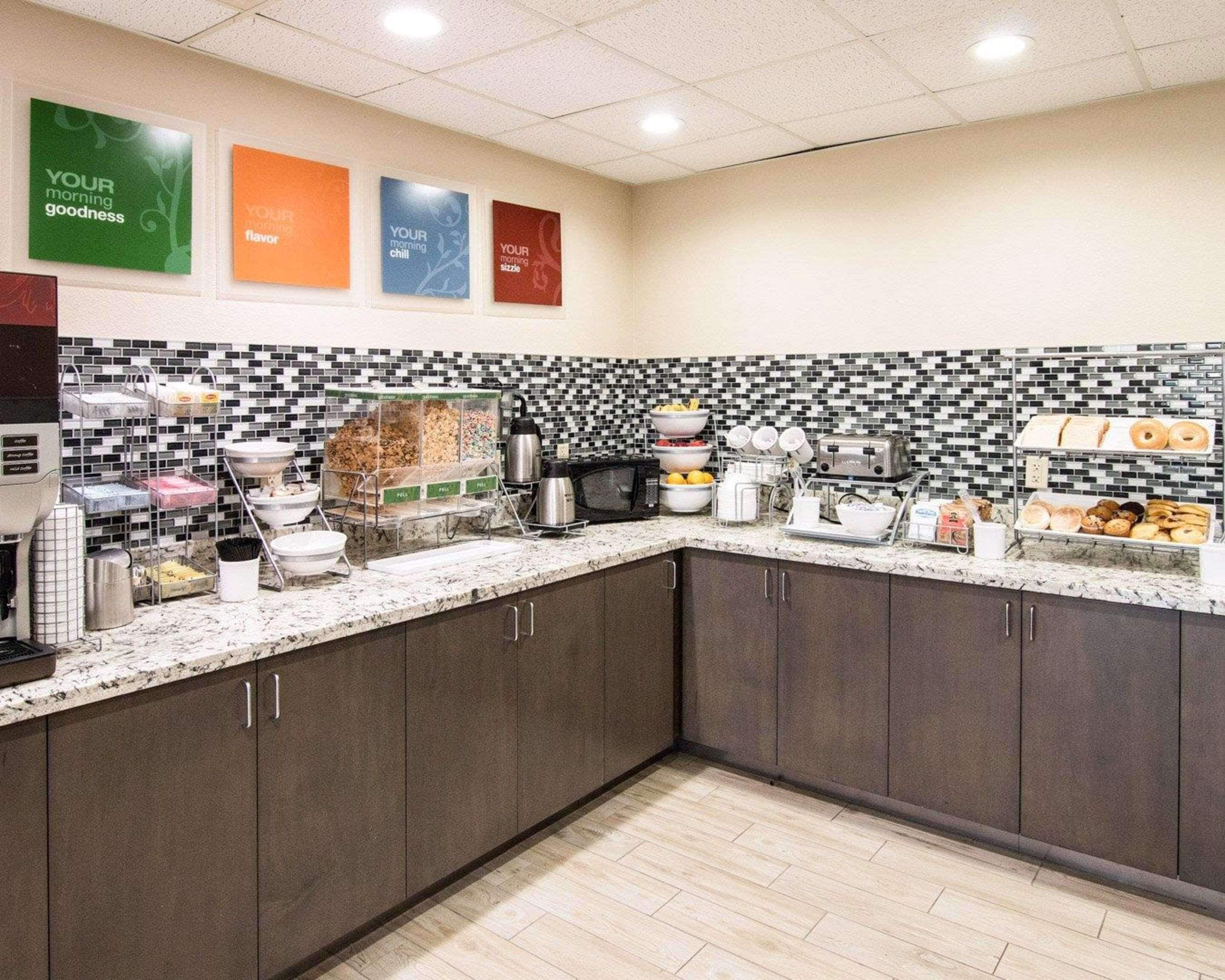 Una cocina moderna con un revestimiento de azulejos blancos y negros, encimera de mármol y diversos productos para el desayuno a la vista.