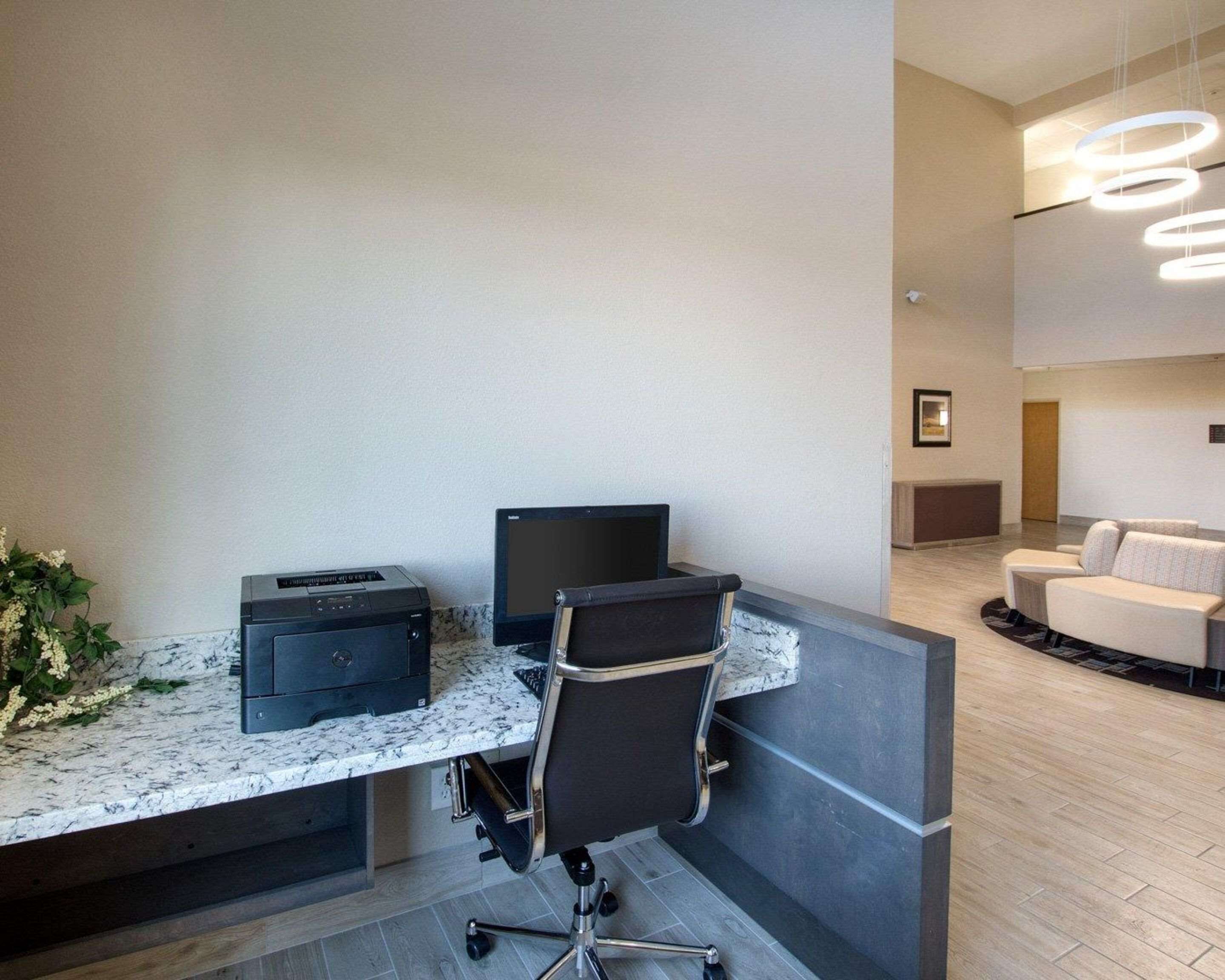 A modern office space with a marble countertop, a black office chair, a printer, and a monitor.