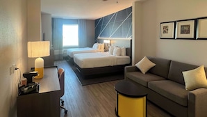 Ett hotellrum med en säng, en soffa, ett skrivbord och en lampa.