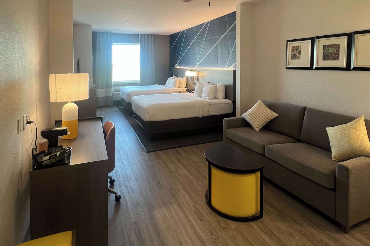 Ett hotellrum med en säng, en soffa, ett skrivbord och en lampa.