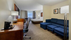 Une chambre d’hôtel équipée d’un bureau, d’une chaise, d’un lit, d’un canapé et d’une lampe.