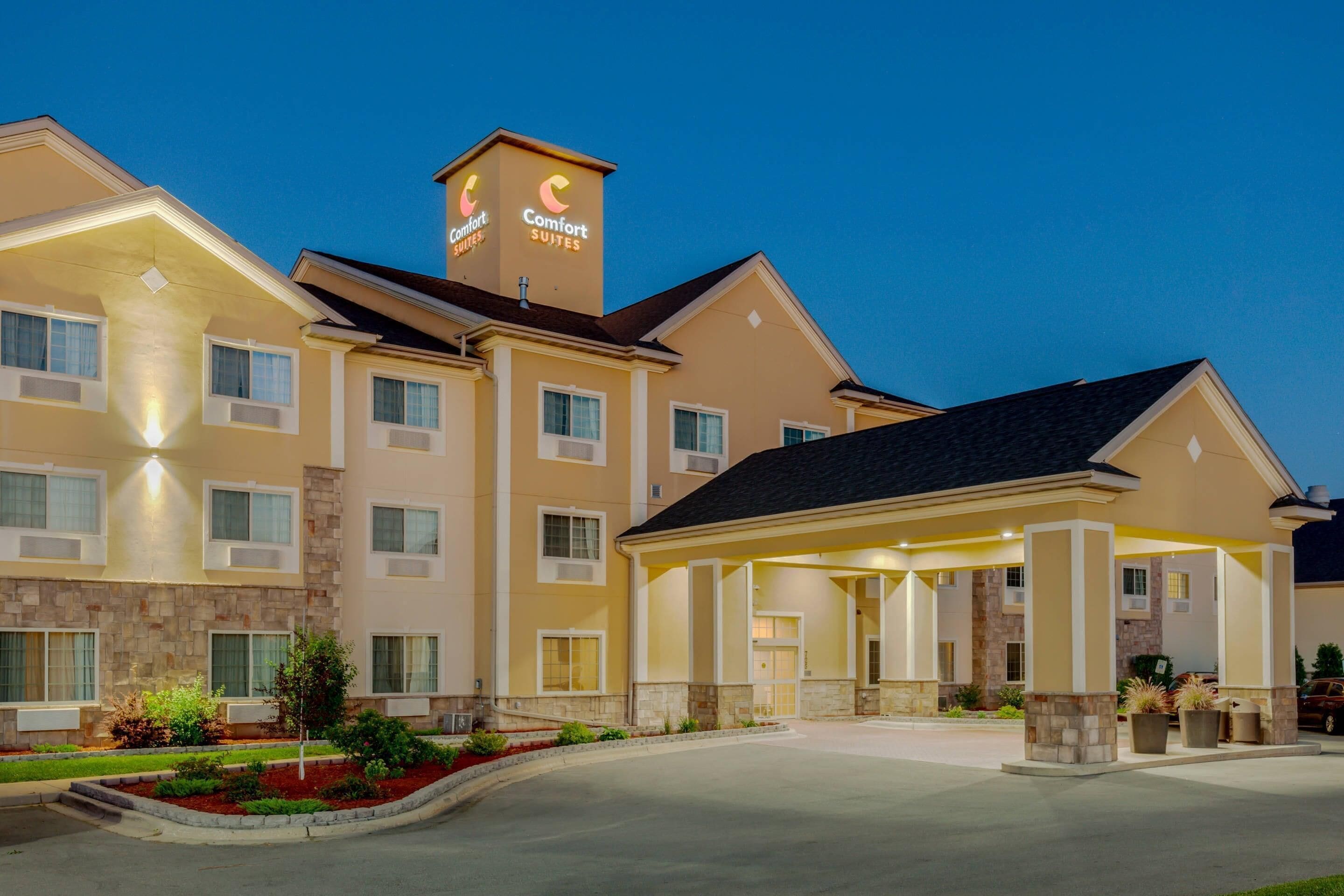 A hotel with a central entrance, multiple windows, and a sign indicating it is a Comfort Suites hotel.