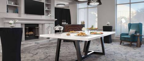 Un comedor moderno con una mesa blanca, sillas negras y una chimenea.