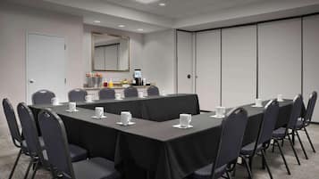 Uma sala de conferências com uma mesa comprida, cadeiras e um canto para café.