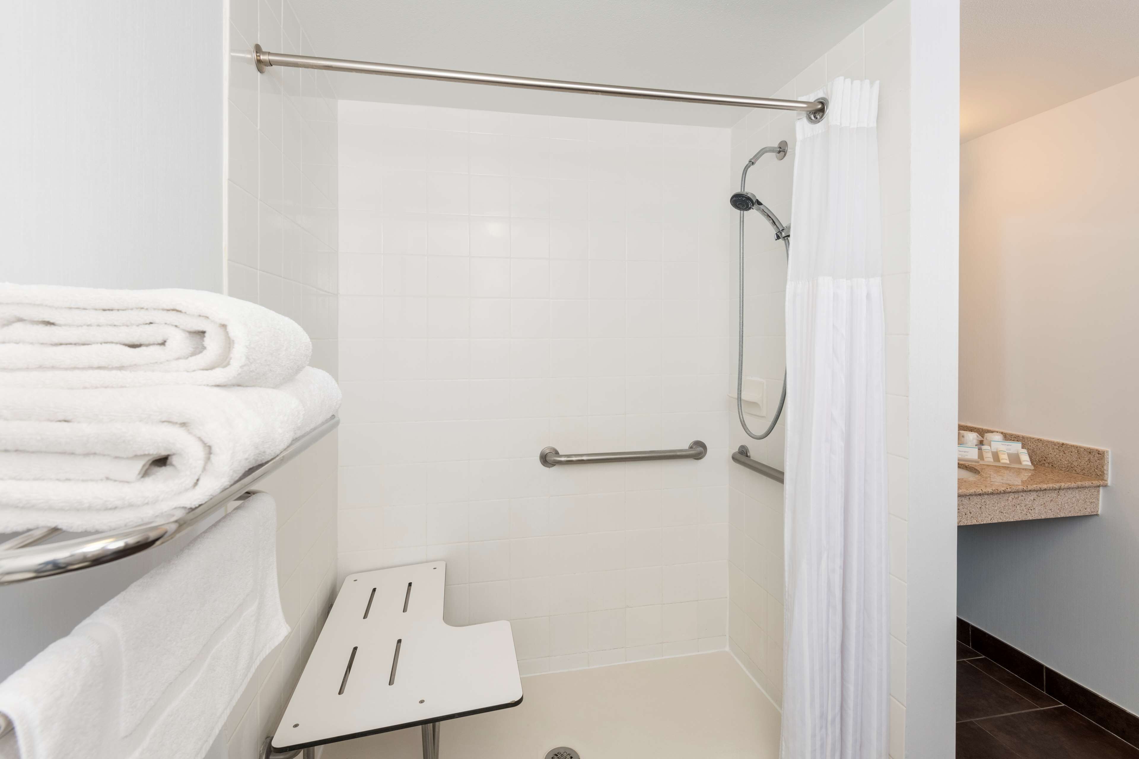 A modern bathroom with a shower, a towel rack, and a small sink area.