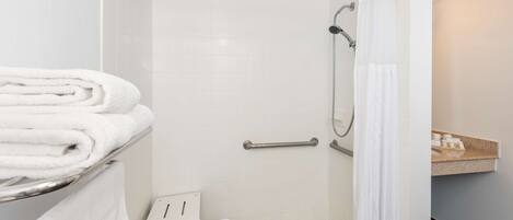 A modern bathroom with a shower, a towel rack, and a small sink area.