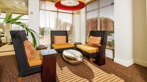 A seating area with wicker chairs, a coffee table, and a large floor lamp. - Hilton Garden Inn Anderson (Anderson)