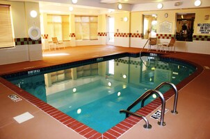 Una piscina con borde de azulejos, una silla de salvavidas y una escalera para la piscina.