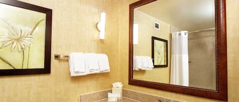 Un baño con un espejo grande, un lavabo y un perchero para toallas.