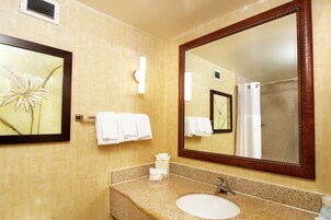 Un baño con un espejo grande, un lavabo y un perchero para toallas.