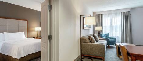 Una habitación de hotel con una cama, un sofá, una mesa de comedor y una lámpara.