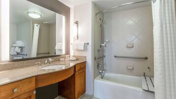 A modern bathroom with a double sink vanity, a large mirror, a walk-in shower with a glass door, and a bathtub.