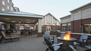 An outdoor patio with Adirondack chairs, a fire pit, and a brick floor. - Homewood Suites by Hilton Albany (Albany)