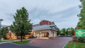 A hotel entrance with a covered driveway, a sign for Homewood Suites, and a brick pathway leading to the entrance. - Homewood Suites by Hilton Albany (Albany)