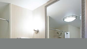 Un baño moderno con cabina de ducha de vidrio, un secador de manos y un espejo con marco decorativo.