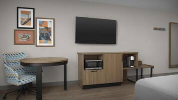 Une chambre d’hôtel avec un lit, un bureau doté d’un micro-ondes, une chaise et des tableaux encadrés au mur.