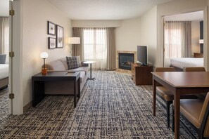 A hotel room with a sofa, a small table, a TV, a fireplace, and a dining area. - Residence Inn by Marriott Columbia (Columbia)