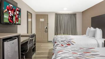 A hotel room with a bed, a desk, a television, and a door.