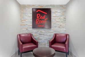 A Red Roof Inn sign with two red leather chairs and a round table in a lobby area. - Red Roof Inn Hope (Hope)