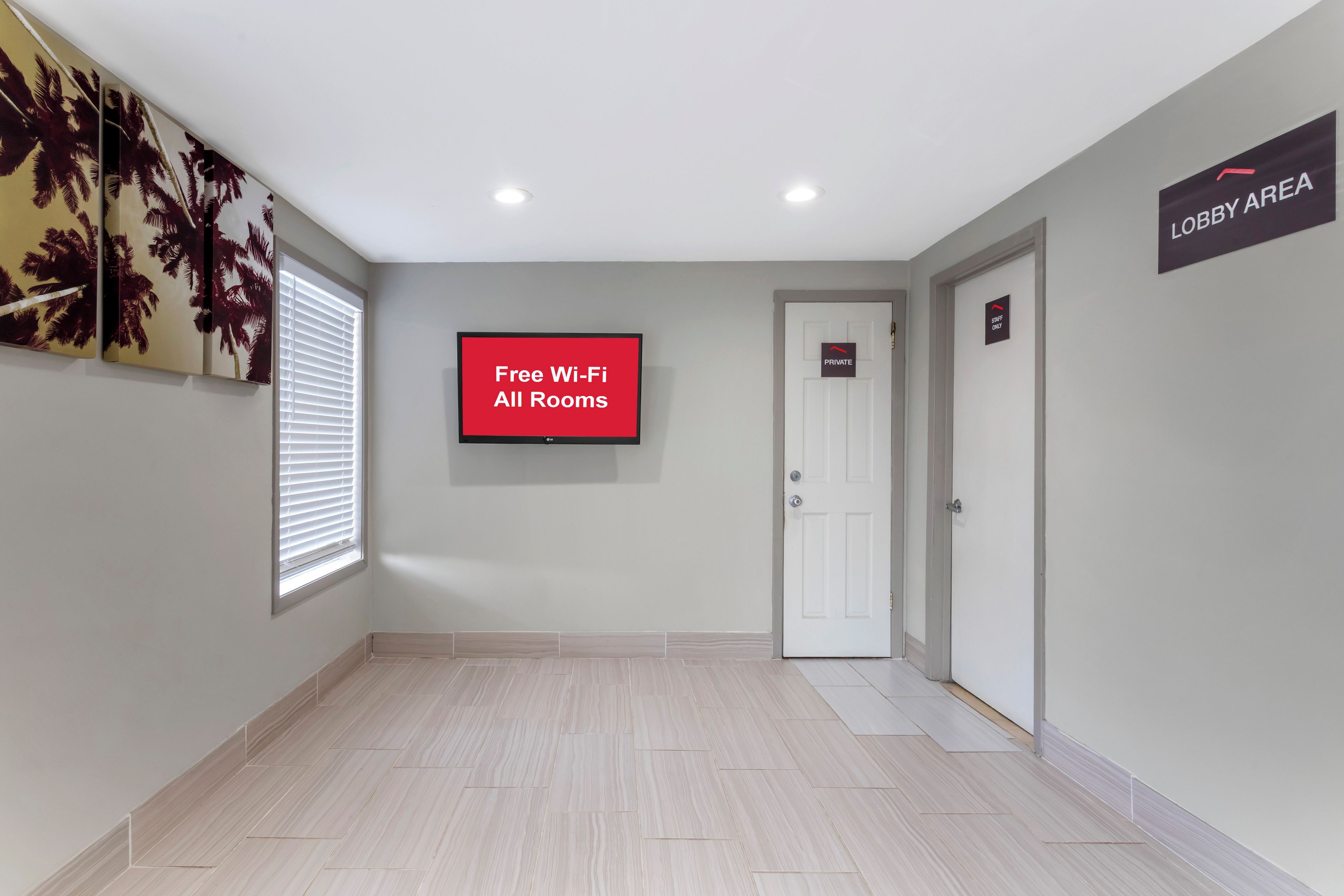 Un couloir avec un panneau indiquant que le Wi-Fi est disponible gratuitement dans toutes les chambres, une porte privative et un panneau indiquant l’entrée du hall.