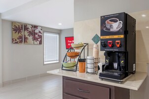 Una cafetera con opciones de café regular, agua caliente y descafeinado, y un frutero sobre la encimera.
