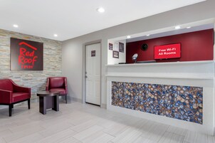 A hotel reception area with a Red Roof Inn sign, a 'Free Wi-Fi All Rooms' sign, and a 'Manager On Duty' sign.